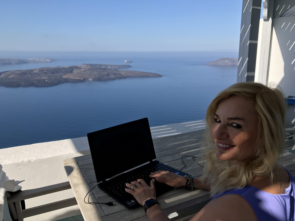 Alexandra sits happily at her computer on the balcony of Gaia, one of our favourite Santorini villas.