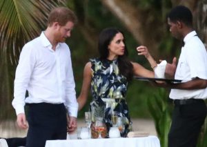 Meghan Markle holding hands with Prince Harry while discussing something with a waiter