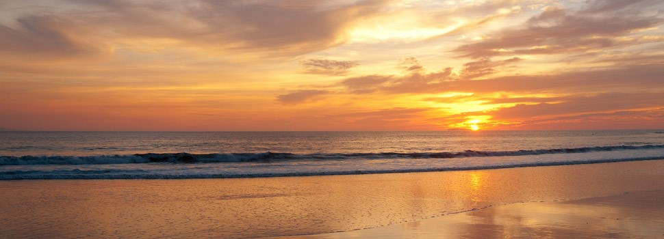 Sunset at a beach at Punta Mita The sun dips towards the horizon behind a wide, peaceful beach at Punta Mita