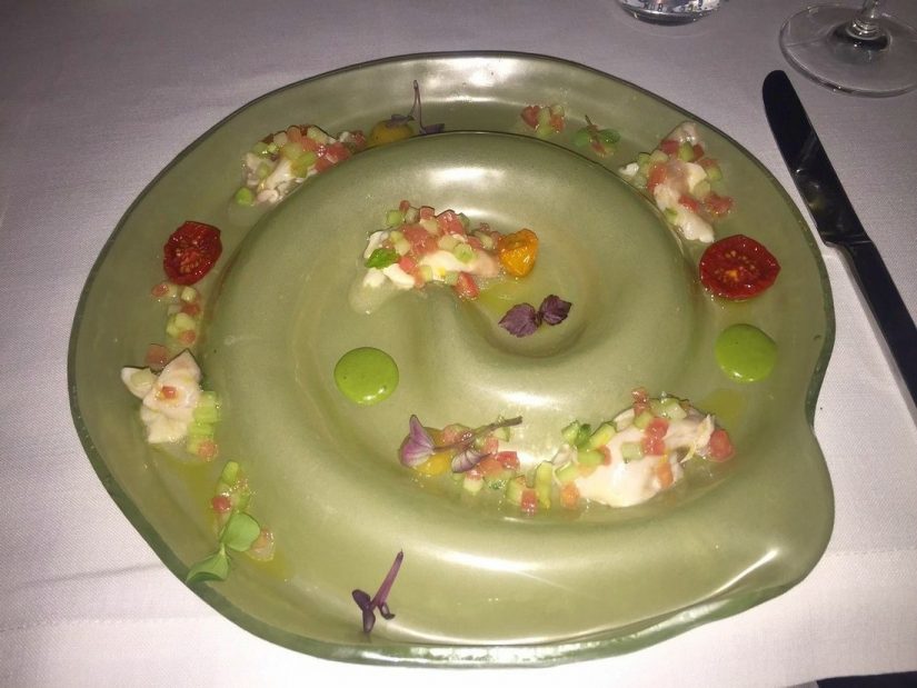 A very artistic dish of sea bass ceviche on a green plate