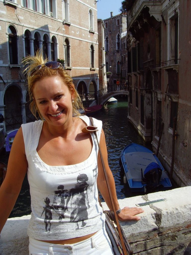 Alexandra Baradi leaning on a bridge in Venice with a canal in the background