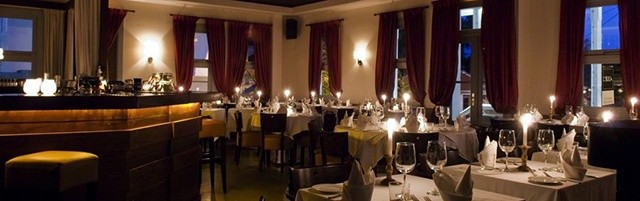 The serenely lit dining area at L'Isola. Candles, richly warm wooden furnishings, and umber tones help to create a romantic ambience.