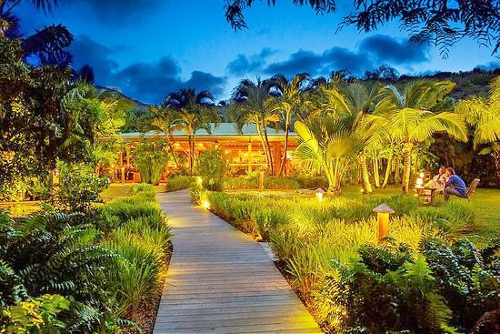 A path of wooden decking leads through the gently lit palm trees and lush foliage to Tamarin restaurant. The restaurant itself looks warm and welcoming with wooden walls and fixtures.