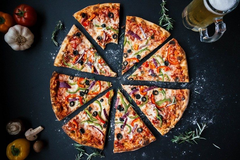 A delicious italian pizza surrounded by fresh ingredients, garlic, tomatoes and peppers