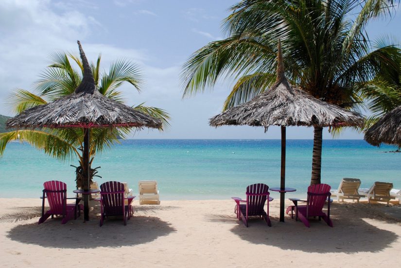 idyllic beach setting, beach chairs under a palm umbrella - bliss