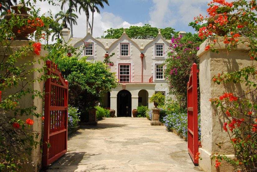 St Nicolas Abbey - A majestic Barbados Attraction sits peacefully among the vibrant red and orange flowers and landscaped gardens.