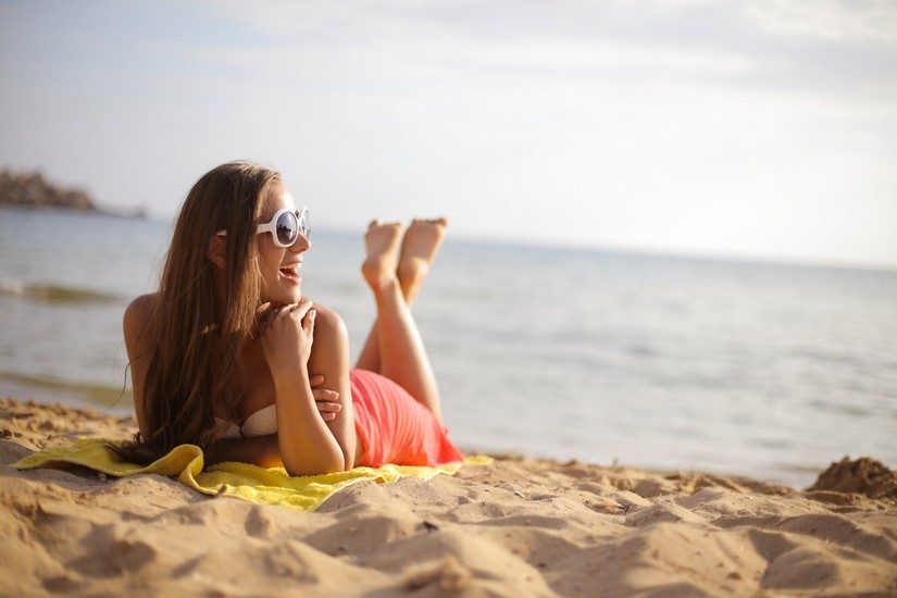 photo-of-woman-wearing-sunglasses-while-lying-on-beach