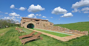 Italian villa set in green fields with a big pool on a sunny day