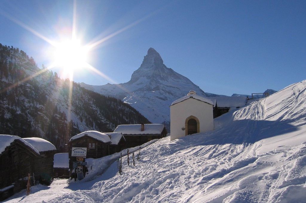 bright morning sun shines over the mountain peaks on chalets in Zermatt