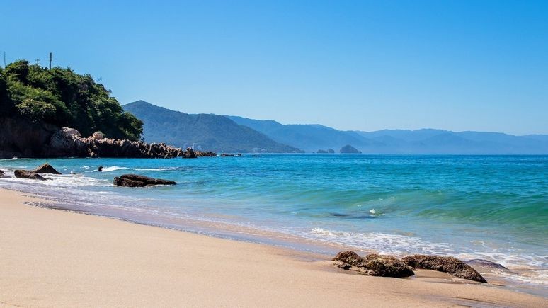 Waves crash onto a golden sand beach in Puerto Vallarta