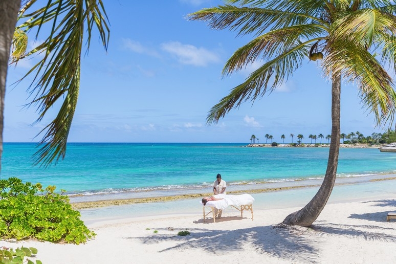 A lady enjoying a massage on the beach at Jumby Bay