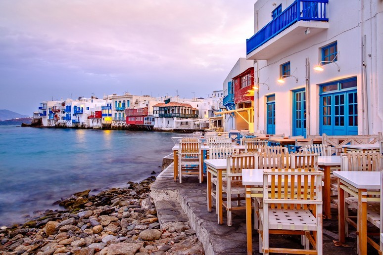 Colouful balconies and window sill project from the white washed buildings of Mykonos the sit directly on the seafront.  It is pretty. 