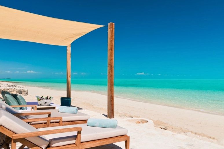 The beach and swaying palm trees at Pearl east villa in on long bay turks and caicos
