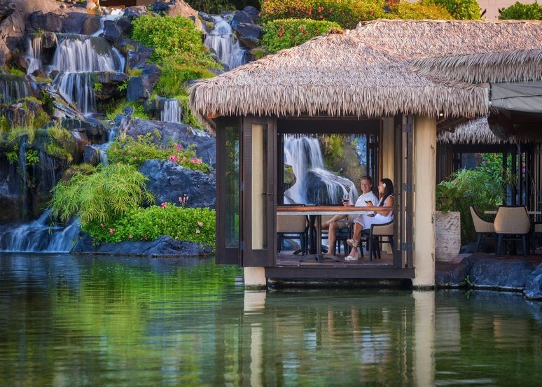 A couple sit by the waterside at the Tidepools restaurant in Kauai