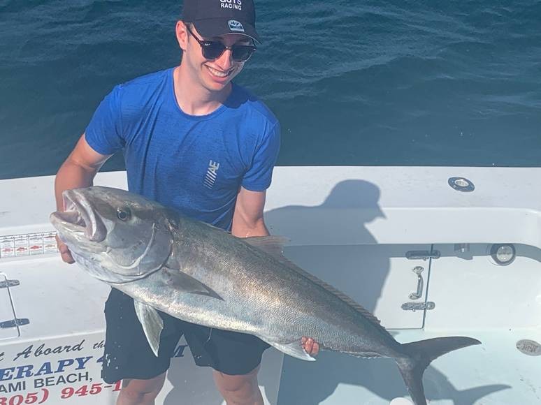 A fisher man on a deep sea fishing trip in Miami holding a massive fish.