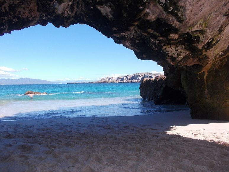 A natural arch spans a sandy beach at puerto vallarta