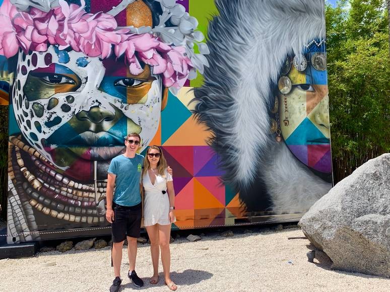 A young couple pose in front of a huge mural in Wynwood Walls, Miami