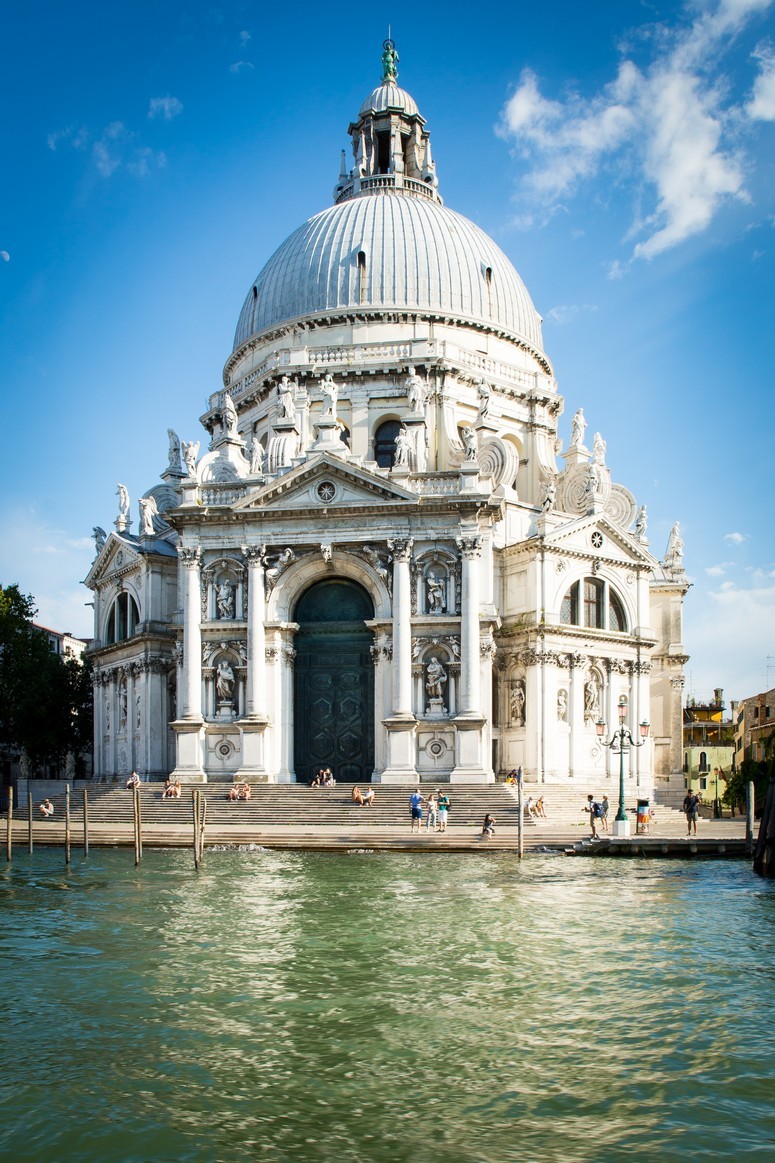 The Santa Maria Della Salute Church with domed roof, statuary, and people sitting on the steps
