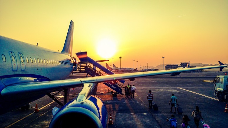 Passengers boarding a plane at sunset