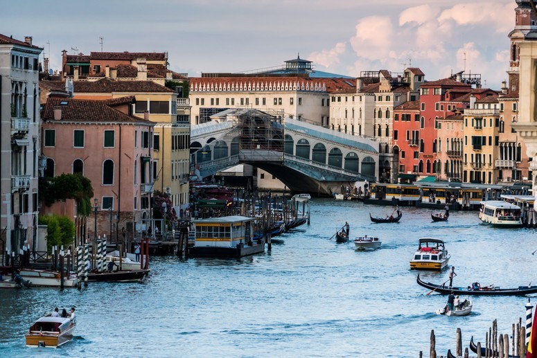 The Rialto Bridge in Venice spans a river busy with ferries and gondolas