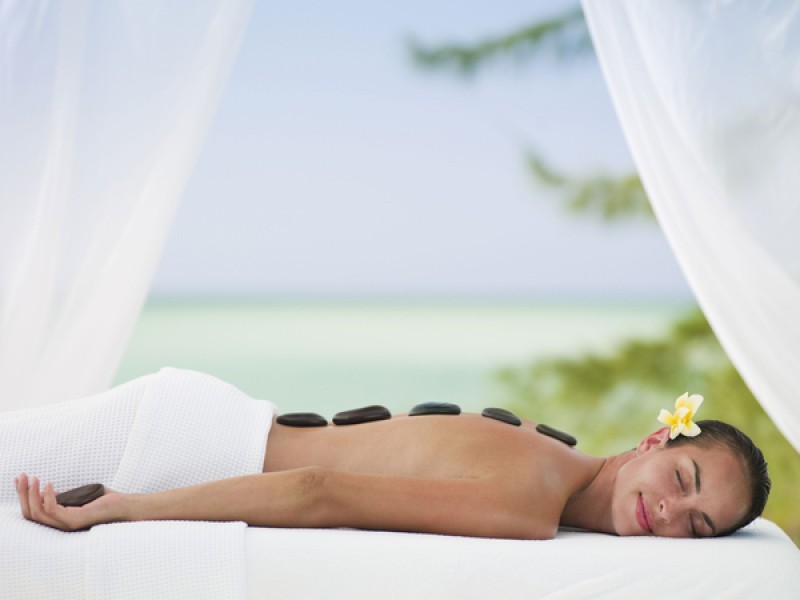 A lady lying down getting warm stone therapy at COMO Parrot Cay in Turks and caicos