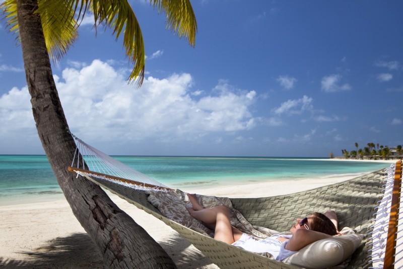Lady relaxes in a hammock at jumby bay beach