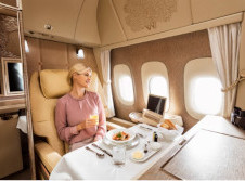 Lady sits in comfort in her own private dining area eating chef prepared food on a regal wings luxury jet