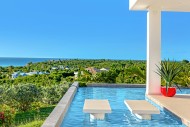 View across the swimming pool outside of Grand Bleu - vividly green palm trees leading all the way u