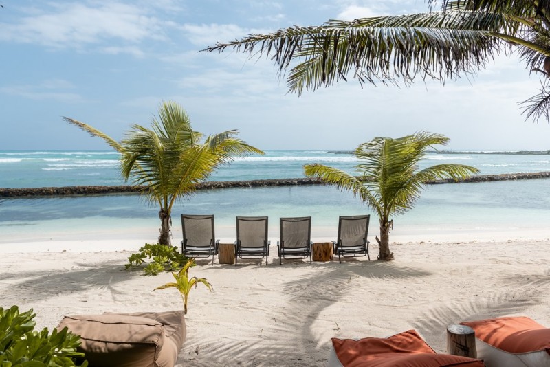 White sandy beach with loungers and palms at Hacienda Corazo