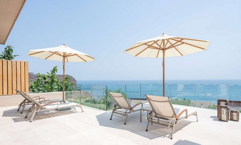Terrace with loungers and parasols overlooking the ocean.