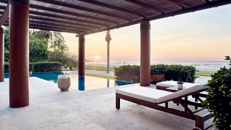 View of sunbeds by the villa pool overlooking the beach