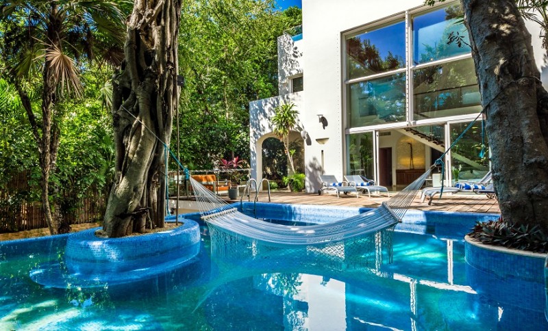 A hammock hanging over the pool and a view of the villa