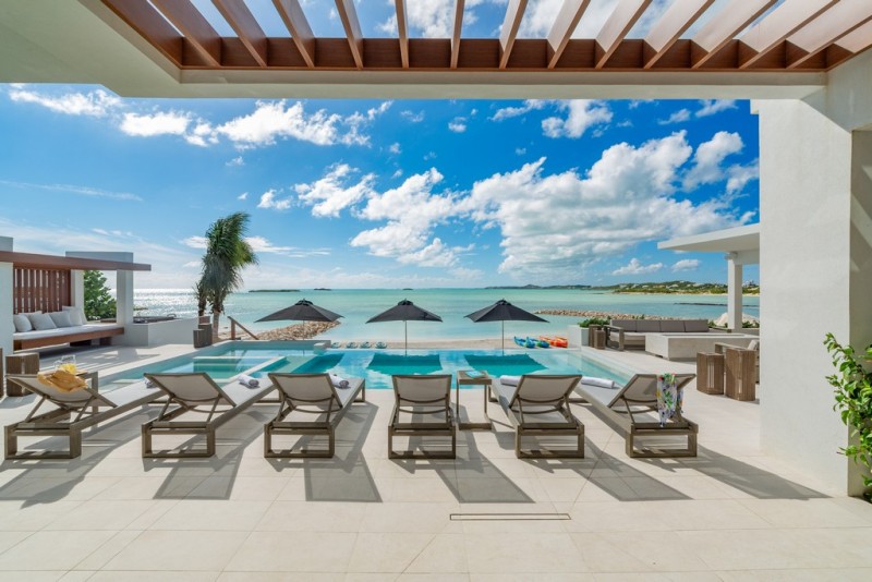 Pool area with loungers, parasols and beach at Solara